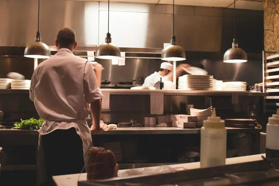 Restoran mutfağında tezgâh başında çalışan bir aşçı